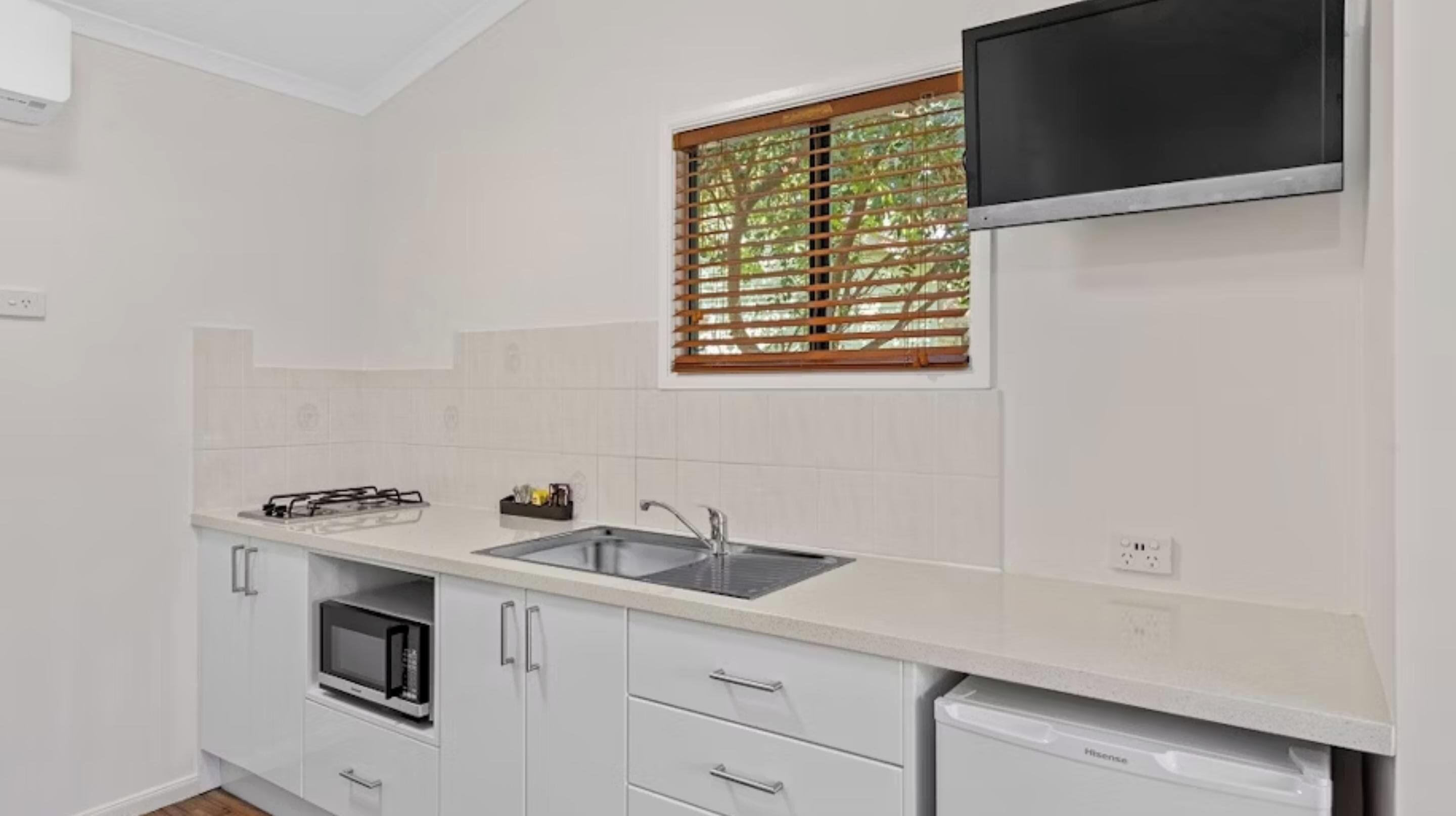 A modern kitchen with white cabinetry, a built-in microwave, a sink, and a dishwasher.