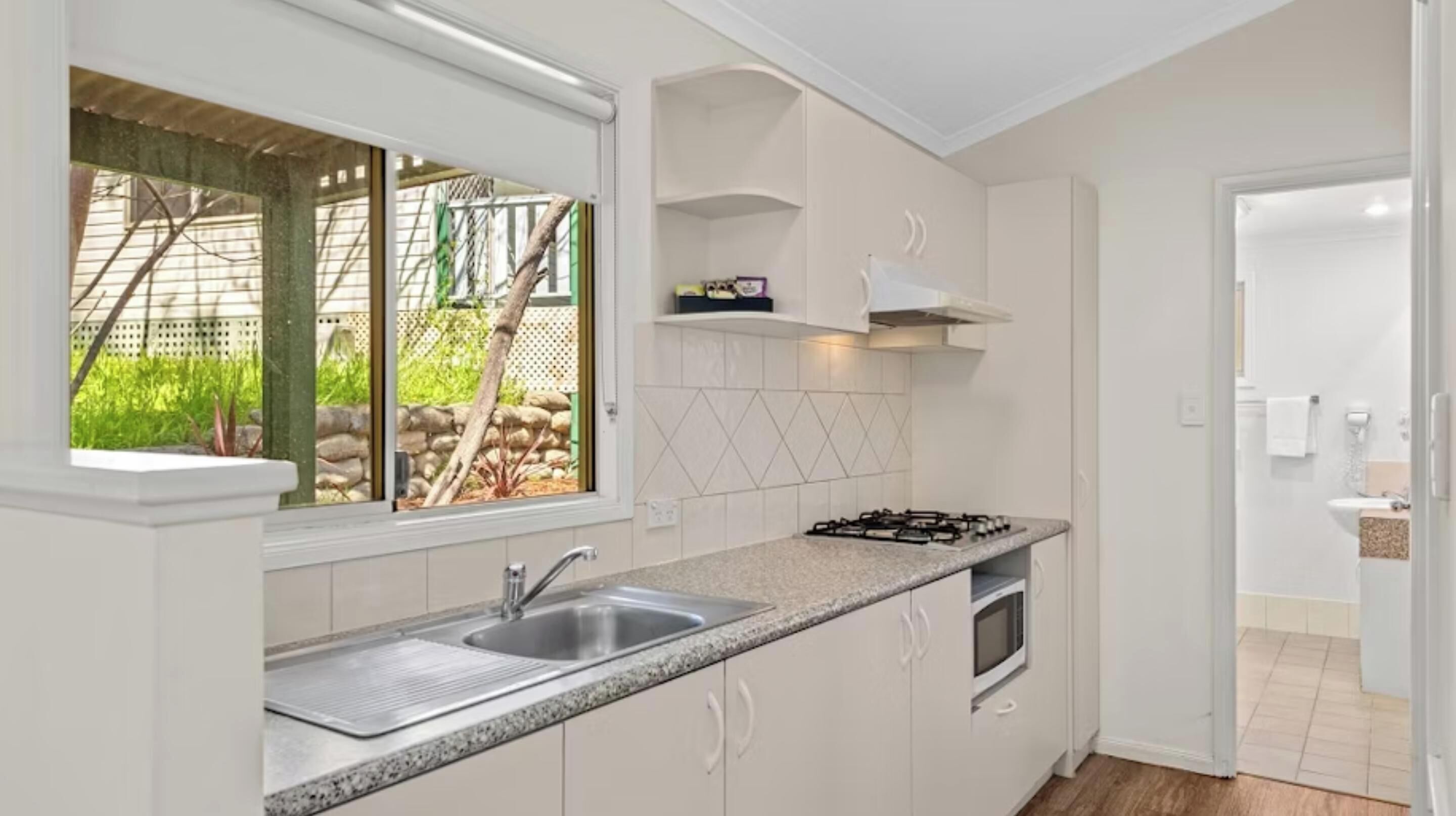 Una cocina moderna con encimera de granito, pileta de acero inoxidable y horno empotrado.