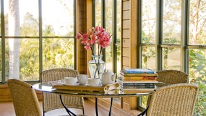 A table with a vase of pink flowers, a stack of cookbooks, and a tray with cups and a teapot. - Summerhills Retreat Byron Bay (Binna Burra)