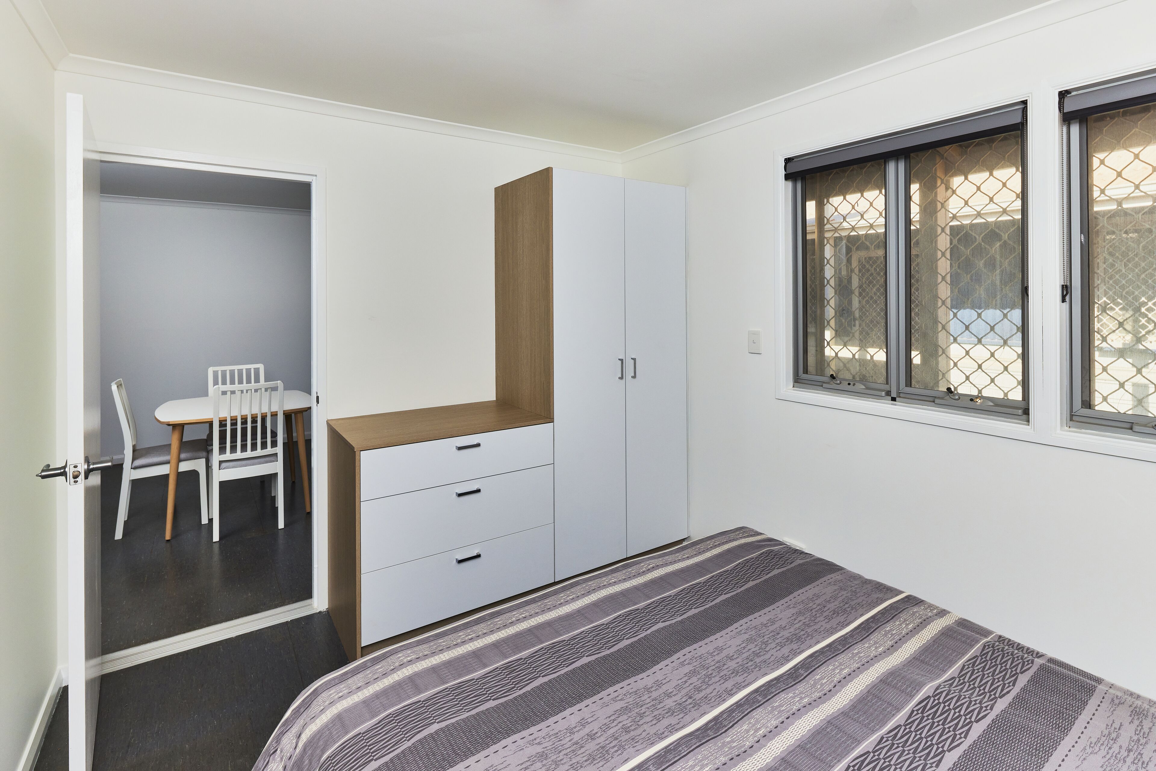 Un dormitorio con cama, escritorio y silla. Hay una ventana que ofrece vistas al exterior.
