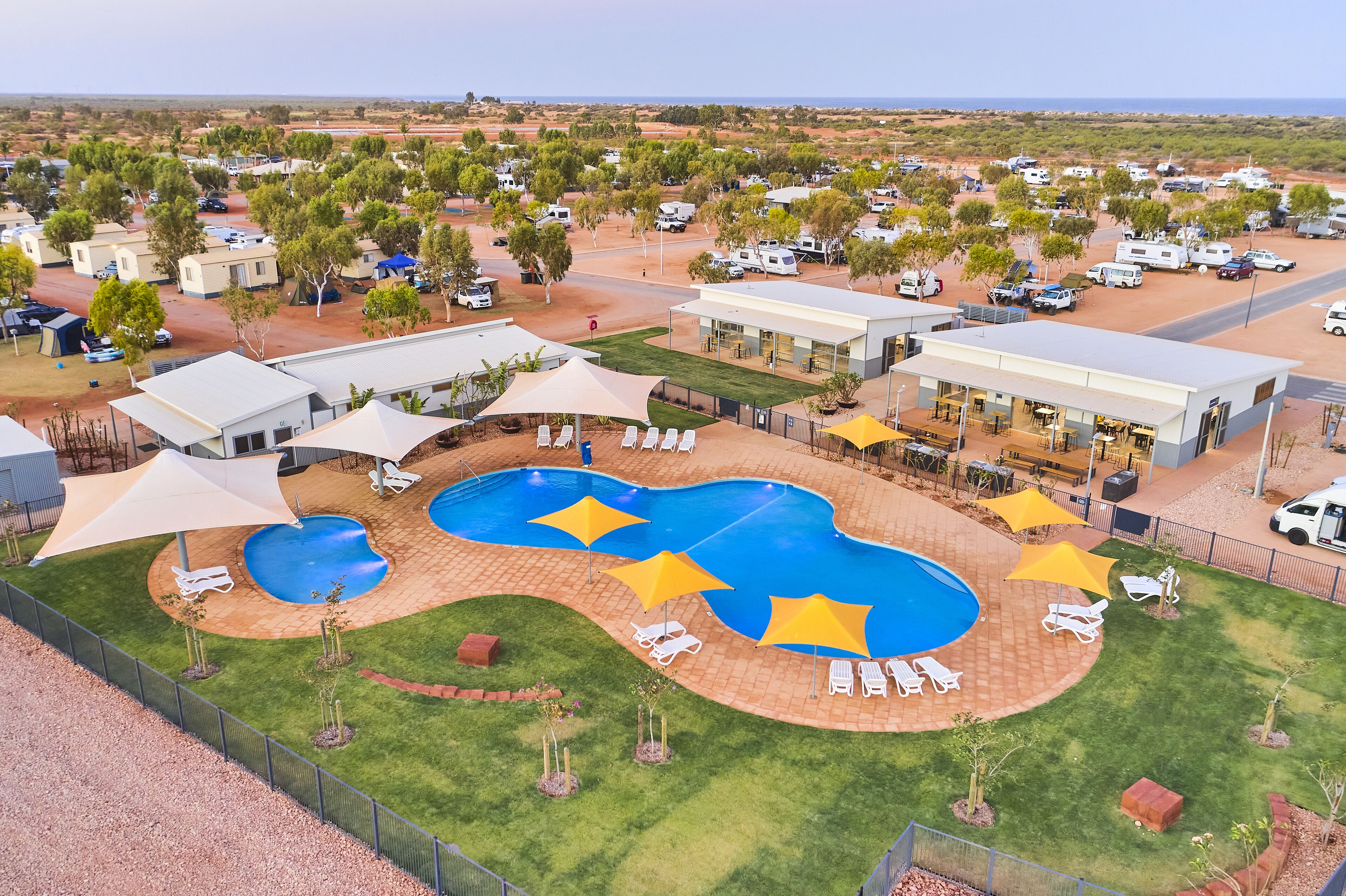 A resort with multiple swimming pools, sun loungers, and a large building with outdoor seating.