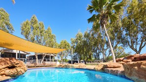 A swimming pool with clear blue water, surrounded by rocks and trees. - RAC Exmouth Cape Holiday Park (Exmouth)
