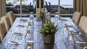 Mesa de comedor preparada para seis personas con vista a un lago a través de amplios ventanales.