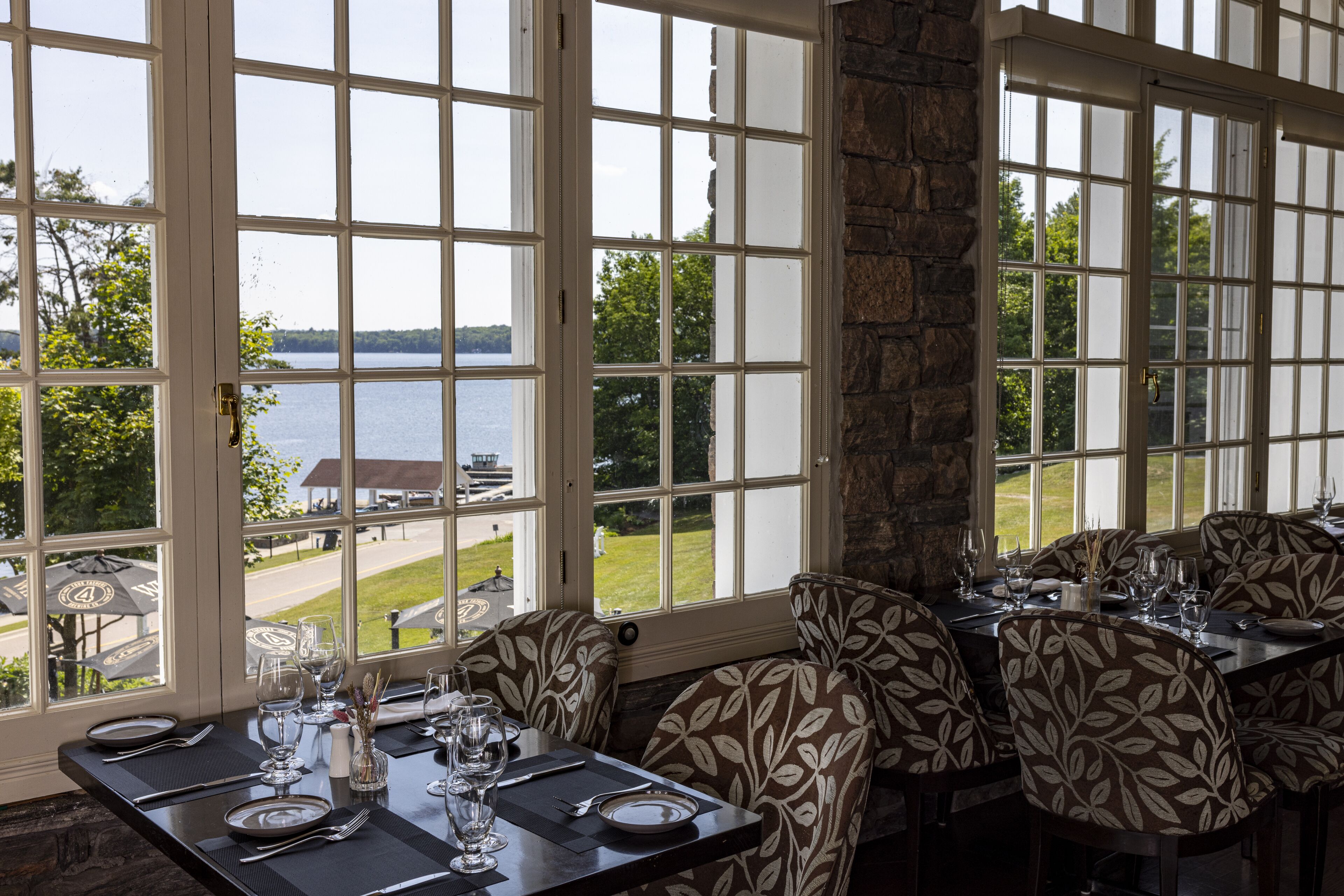 A dining area with large windows, a stone pillar, and a view of a lake and golf course.