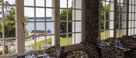 A dining area with large windows, a stone pillar, and a view of a lake and golf course.