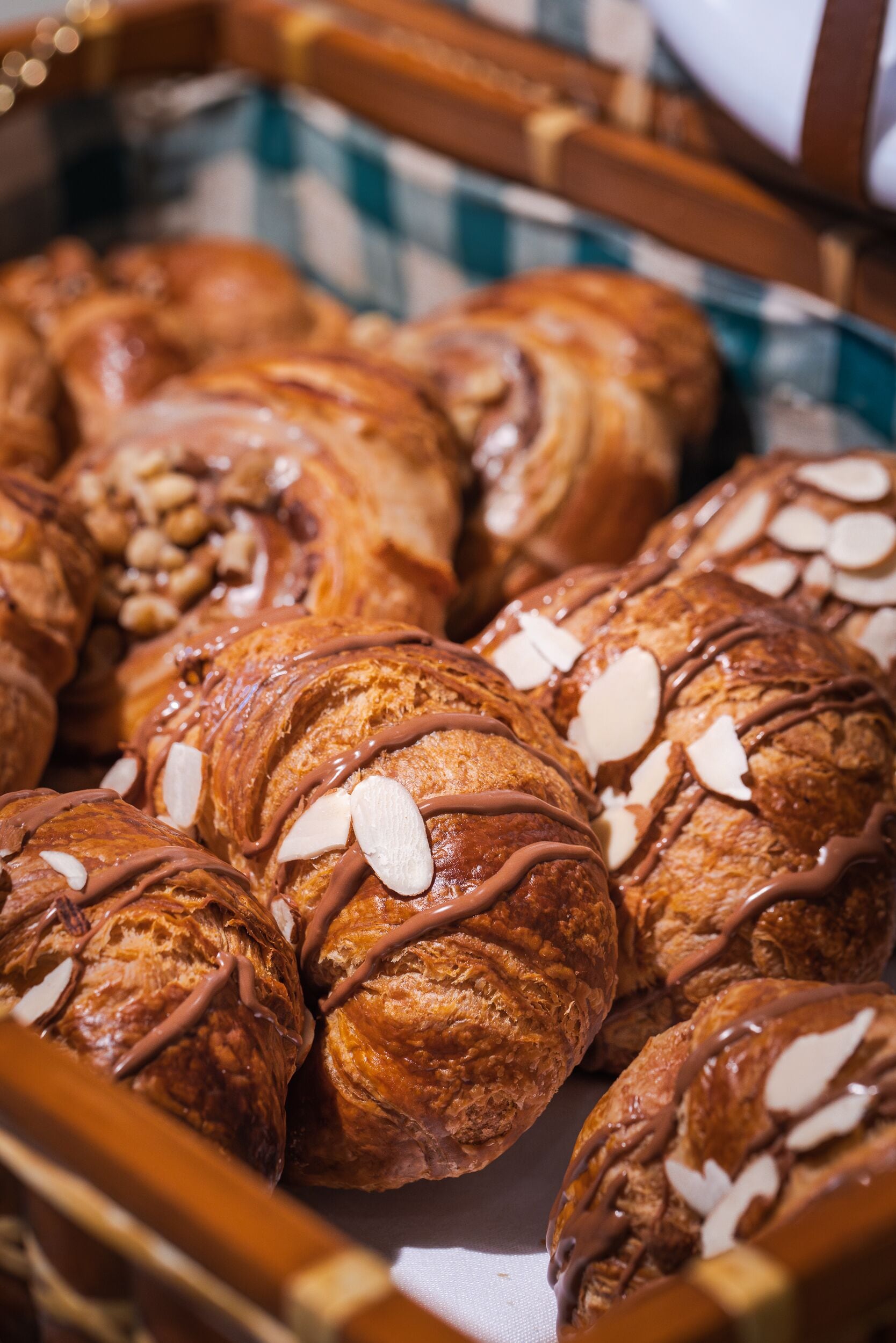 Una cesta de cruasanes con glaseado de chocolate y almendras laminadas.