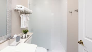 A modern bathroom with a shower, a toilet, a sink with a mirror, and a towel rack.