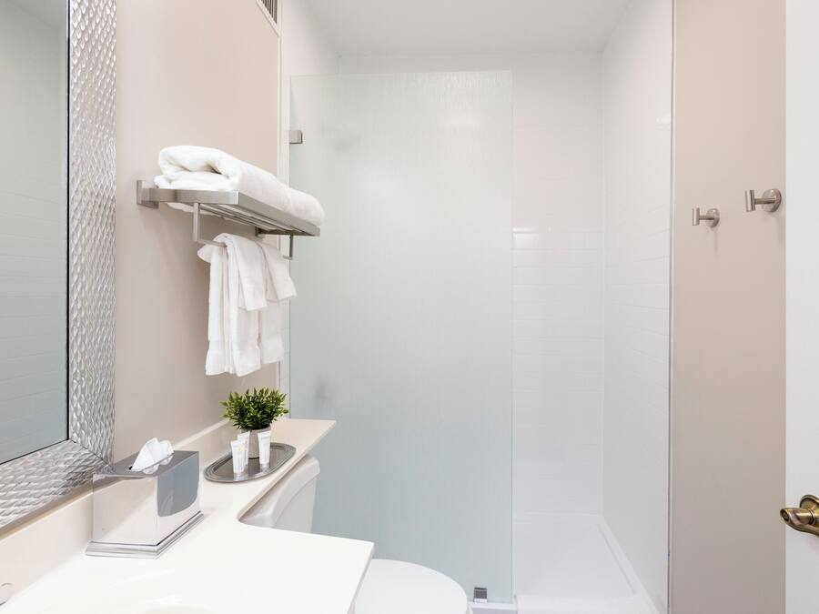 A modern bathroom with a shower, a toilet, a sink with a mirror, and a towel rack.