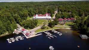 An aerial view of a large resort with a main building, multiple smaller structures, and a marina with boats.