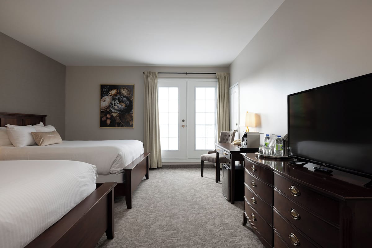 Une chambre d’hôtel avec deux lits, un bureau avec une télévision et un tableau au mur.
