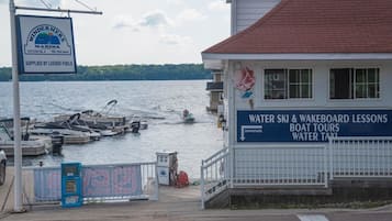 A marina with boats docked, a sign for water ski and wakeboarding lessons, and a building with a red roof.