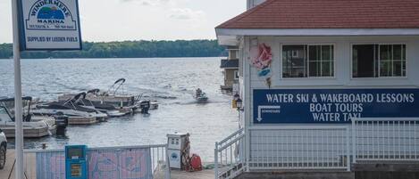 A marina with boats docked, a sign for water ski and wakeboarding lessons, and a building with a red roof.