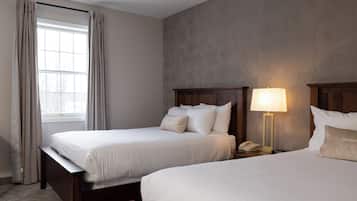 Habitación de hotel con dos camas, una ventana con cortinas, una mesita de noche con lámpara y un teléfono.