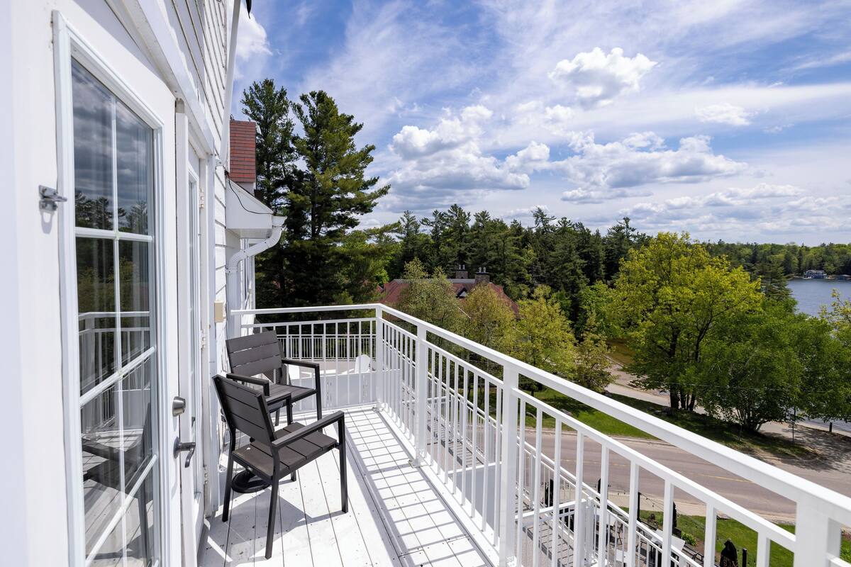 Un balcon avec une balustrade blanche, une table et deux chaises.