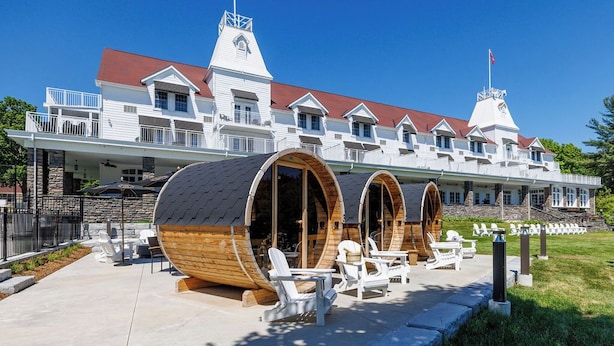 Un hotel con un estilo arquitectónico distintivo, que presenta grandes estructuras en forma de barriles de madera, un exterior blanco y un techo rojo.