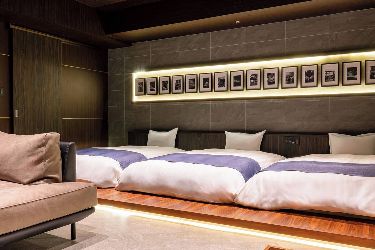 Una habitación de hotel moderna con una cama grande, un sofá y una exposición fotográfica en la pared.