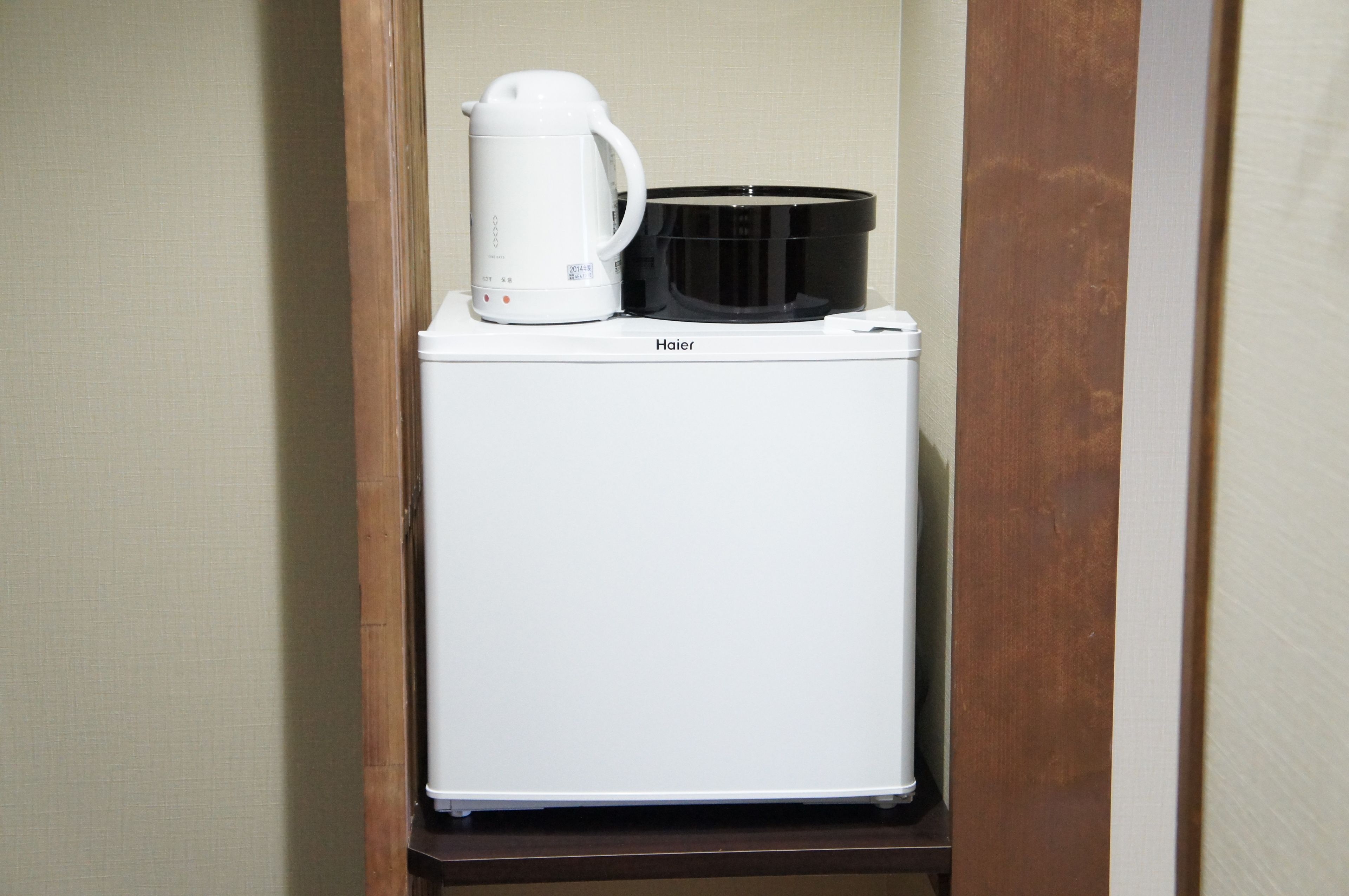Un appareil compact et blanc, doté d’une machine à café et d’un récipient noir, qui ressemble probablement à une mijoteuse, est posé sur un plan de travail blanc.