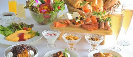 Un assortiment de produits alimentaires comprenant une salade, des croissants, du saumon fumé et des desserts.