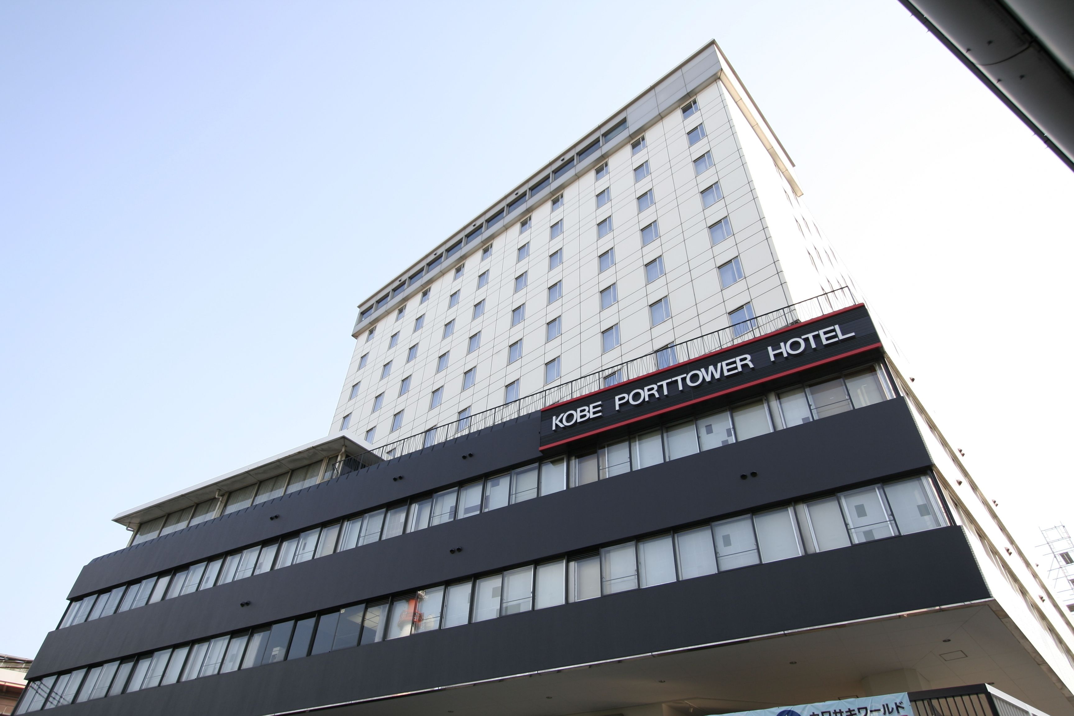 Um edifício de vários andares com uma placa que diz 'Kobe Porttower Hotel'.