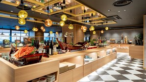 A modern restaurant with a checkered floor, hanging spherical light fixtures, and a variety of dishes and drinks displayed on wooden counters. - Kobe PortTower Hotel (Kobe)