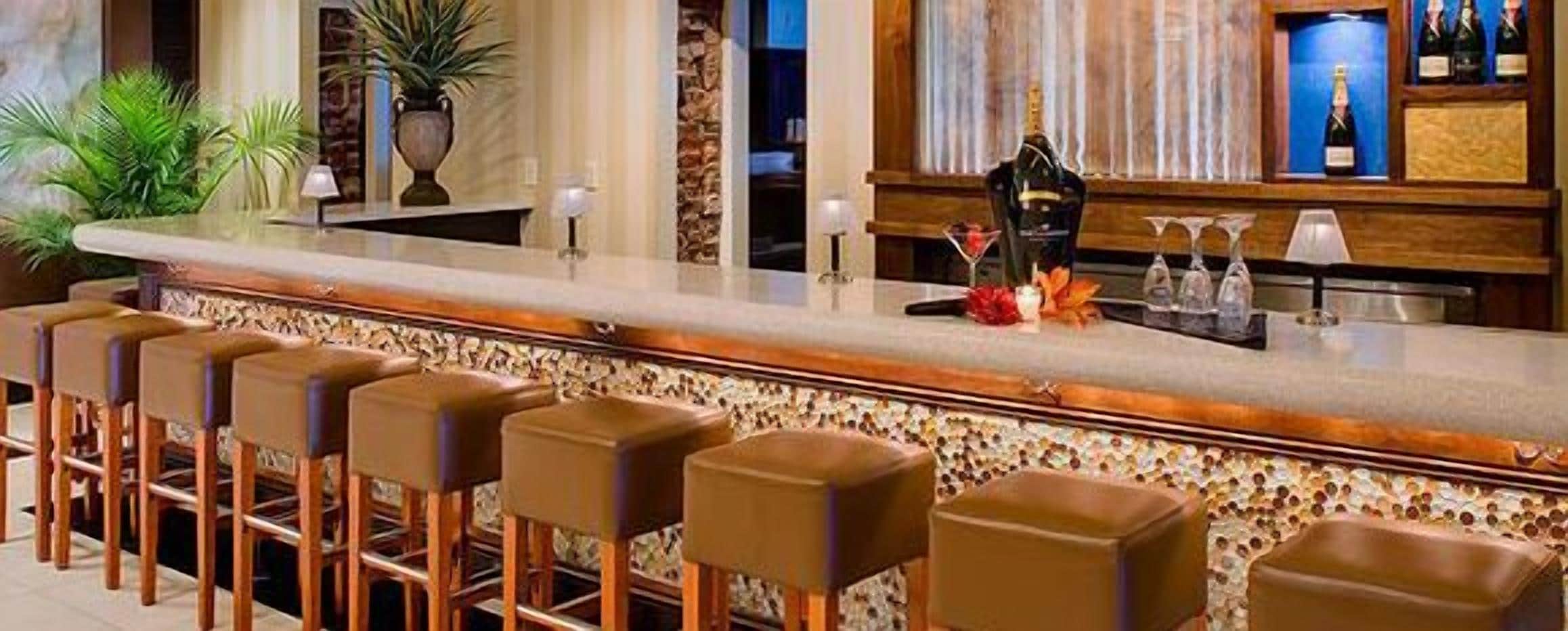 A bar area with a long counter, multiple stools, and a decorative centerpiece.