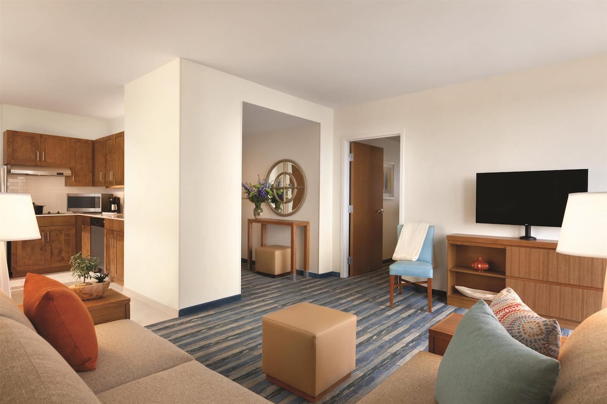 Una habitación de hotel moderna con sala de estar, kitchenette y televisor.