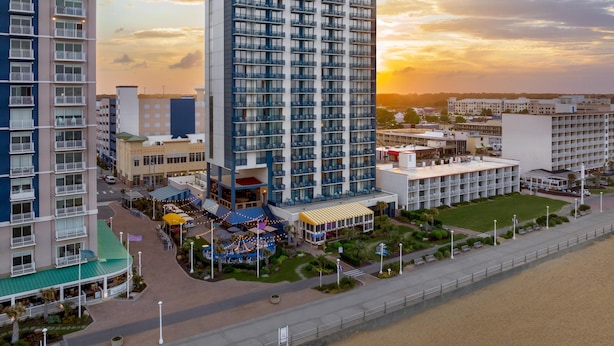A high-rise hotel with multiple balconies, a rooftop bar, and a landscaped courtyard. - Hyatt House Virginia Beach / Oceanfront (Virginia Beach)