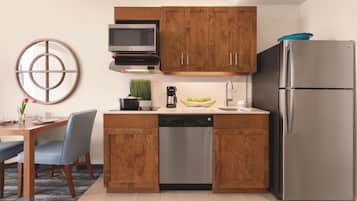 Eine moderne Küche mit Holzschränken, einem Edelstahlkühlschrank, einer Mikrowelle und einer Kaffeemaschine.