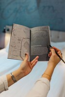 Uma pessoa segurando um livro com um mapa e texto na página esquerda, e uma caneta na página direita.