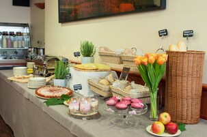 A buffet with various food items, including bread, pastries, and fruits.