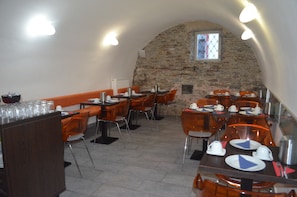 A restaurant with stone walls, orange chairs, and tables set for dining. - Hotel Peregrin (Cesky Krumlov)