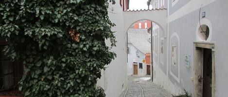 Un carreró empedrat estret amb un edifici a la dreta que mostra un rètol amb la paraula "ŠATLAVSKA".