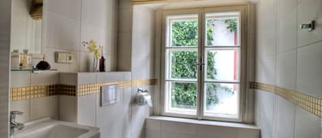 A bathroom with a window, a sink, and a toilet.