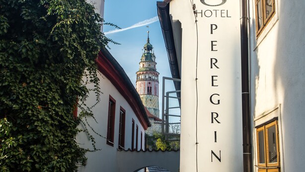 A building with a sign reading "HOTEL OPERGRIN" and a tower in the background. - Hotel Peregrin (Cesky Krumlov)