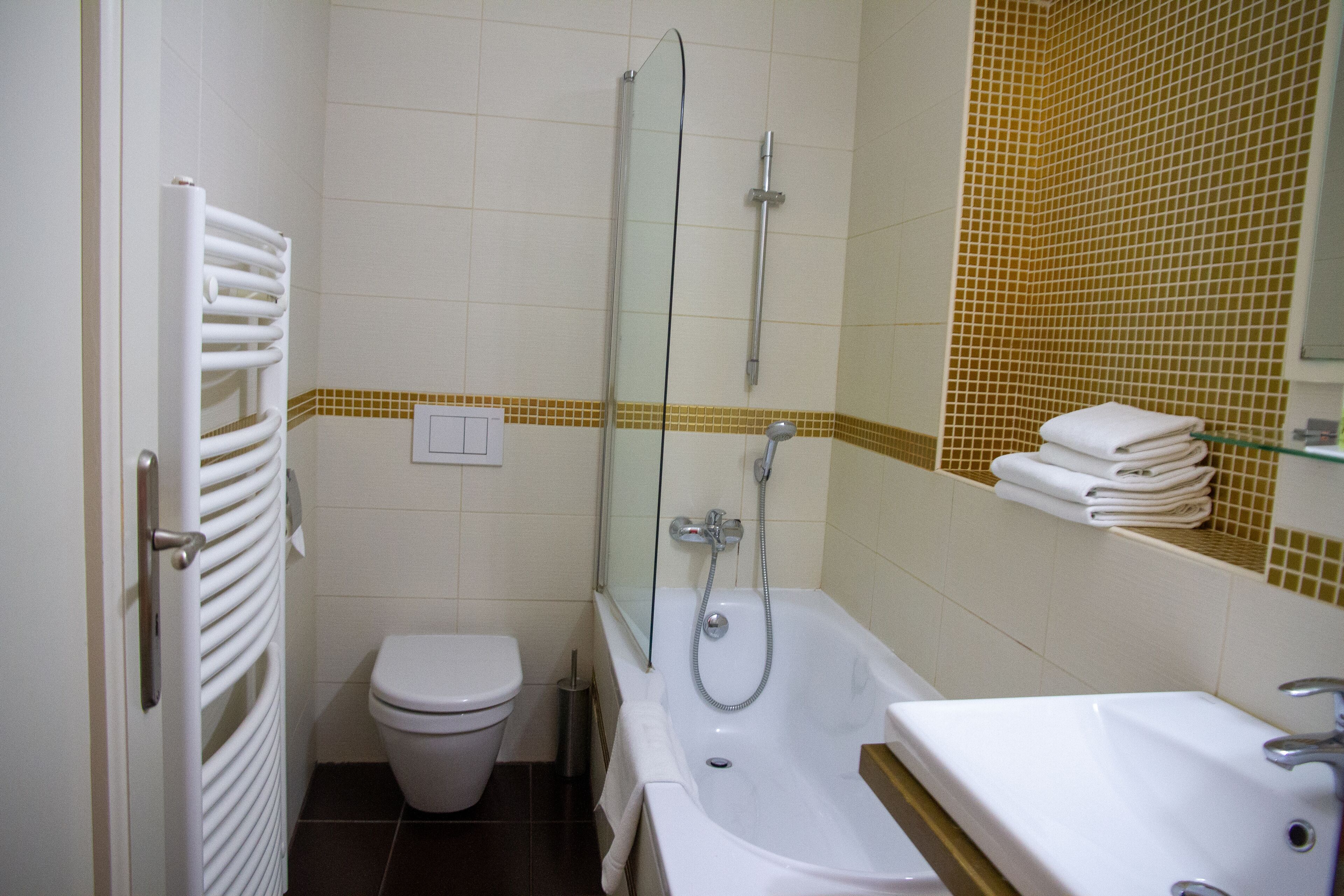 A bathroom with a toilet, a bathtub with a glass-enclosed shower, and a sink.