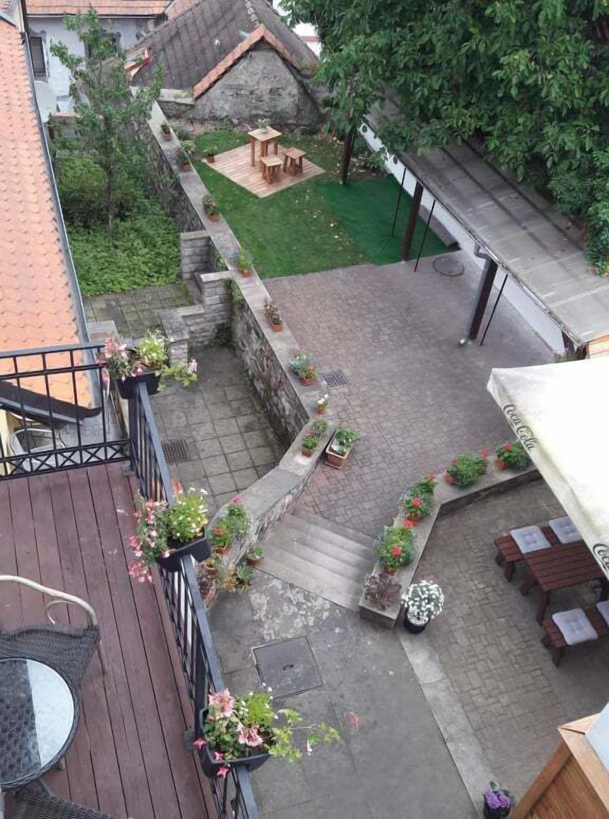 A rooftop patio with a wooden deck, outdoor seating, and potted plants.
