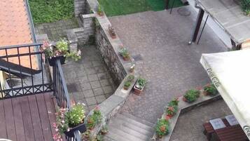 A rooftop patio with a wooden deck, outdoor seating, and potted plants.