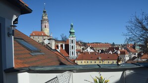 A balcony with wicker chairs and a table with a vase of flowers. - Hotel Peregrin (Cesky Krumlov)
