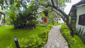 Un vialetto in pietra conduce a un edificio con una porta rossa, immerso nel verde e con un prato curato.