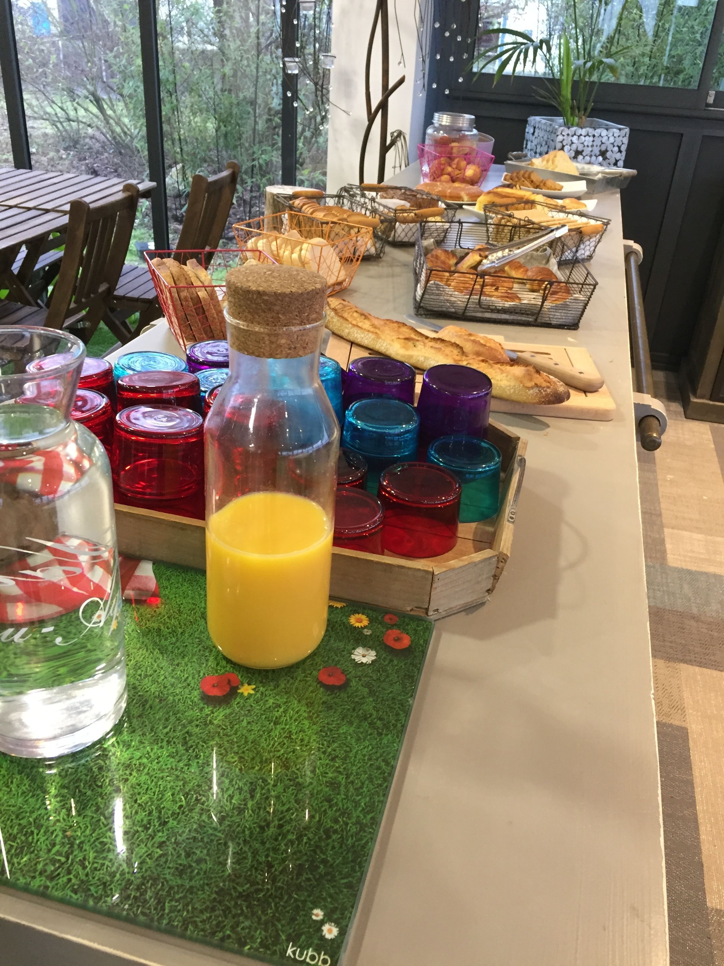 Un bufé de desayuno con panes, pastelería y frascos de vidrio de colores.