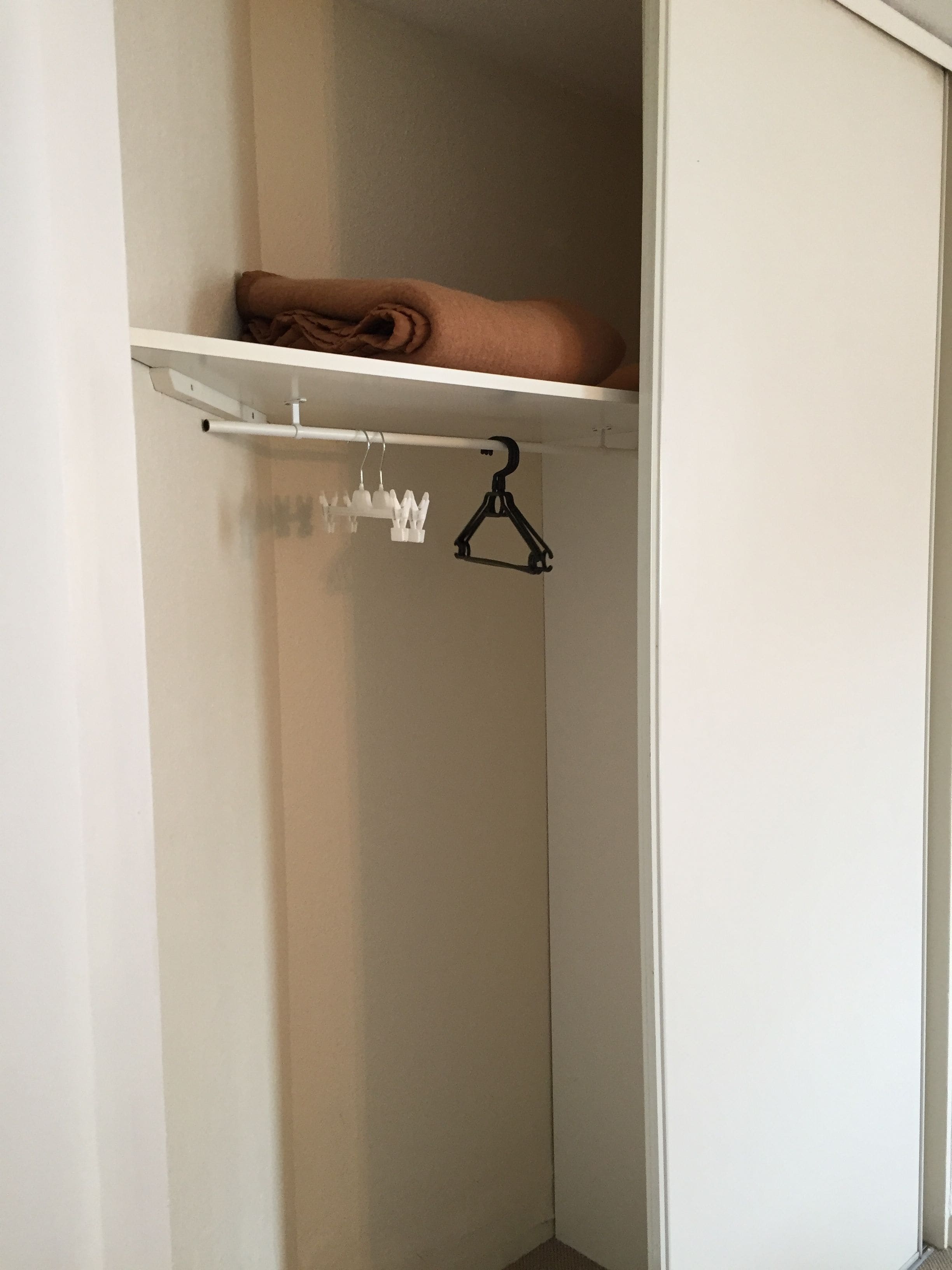 A closet with a hanging rod and a shelf.