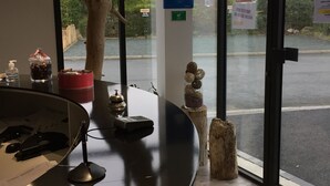 Una reception con un’opera scultorea a forma di albero in legno, un cartello Wi-Fi e vista sul parcheggio tramite ampie finestre.