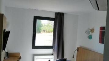A hotel room with a bed, a desk, and a window.