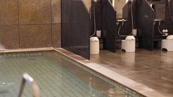A modern bathroom with a pool, multiple showerheads, and a tiled floor.