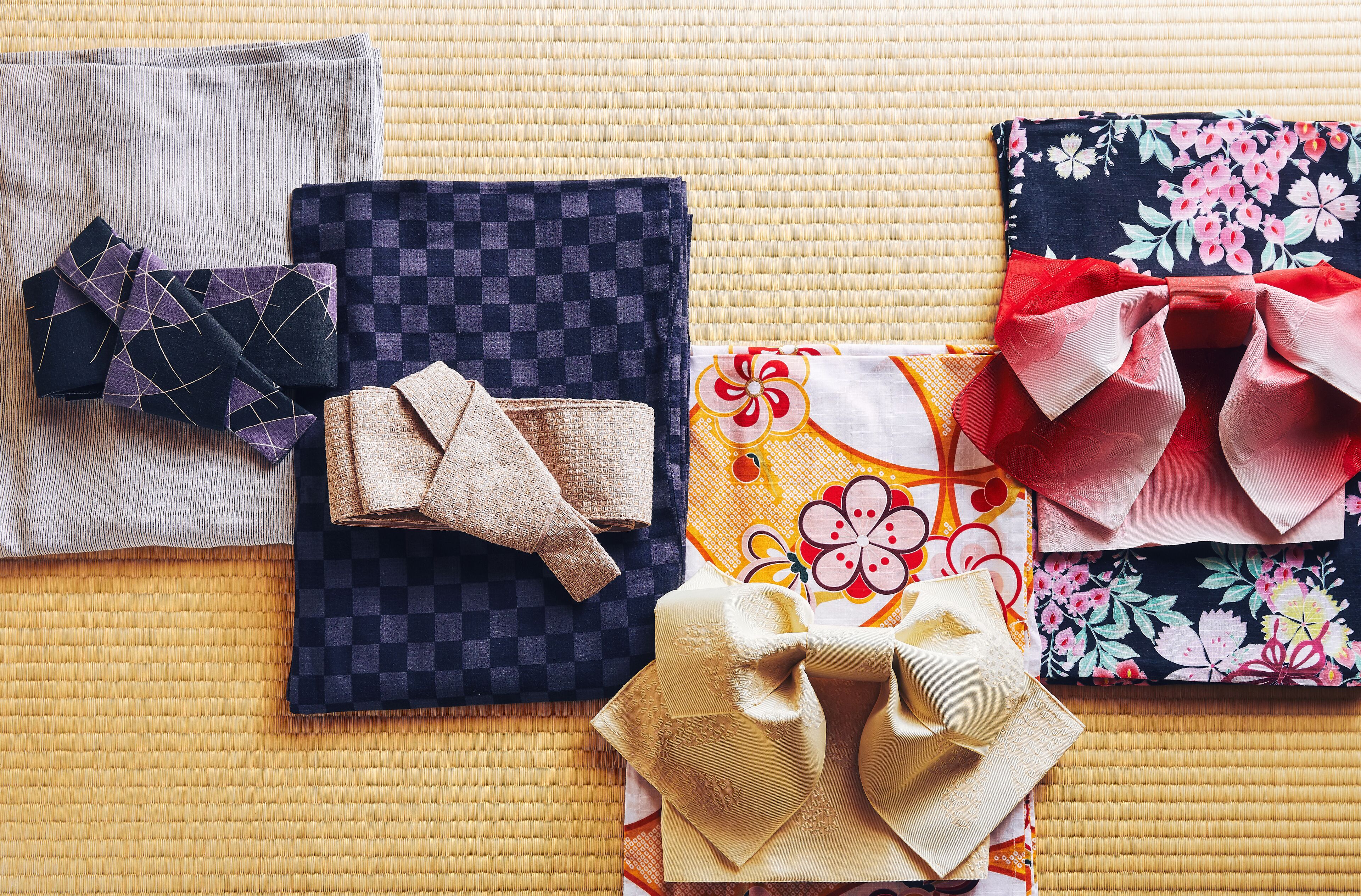 Neatly folded traditional Japanese textiles with various patterns and colors, arranged on a textured surface.