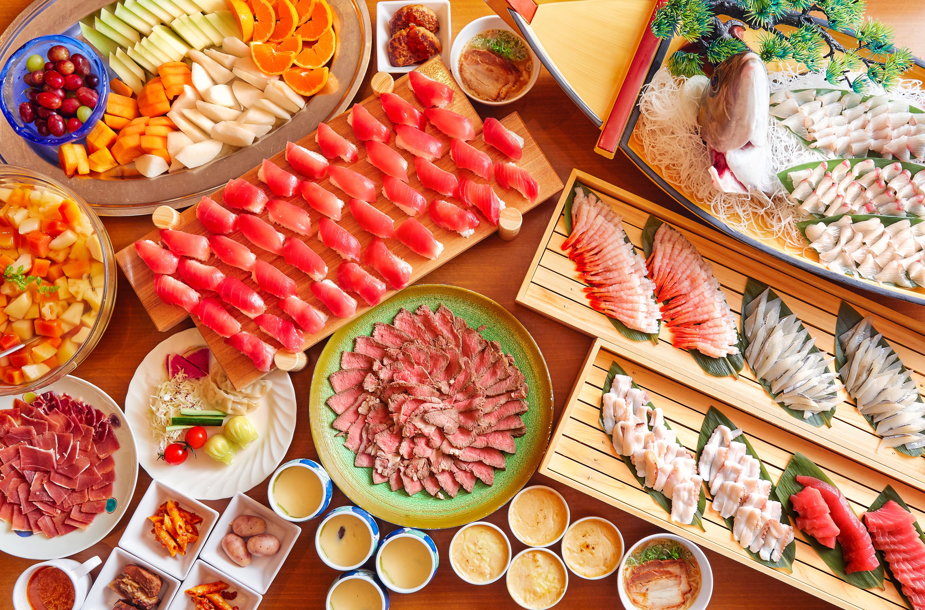 Diverse sushi en sashimi op houten schalen, met kleine schaaltjes sojasaus en ingemaakte gember.