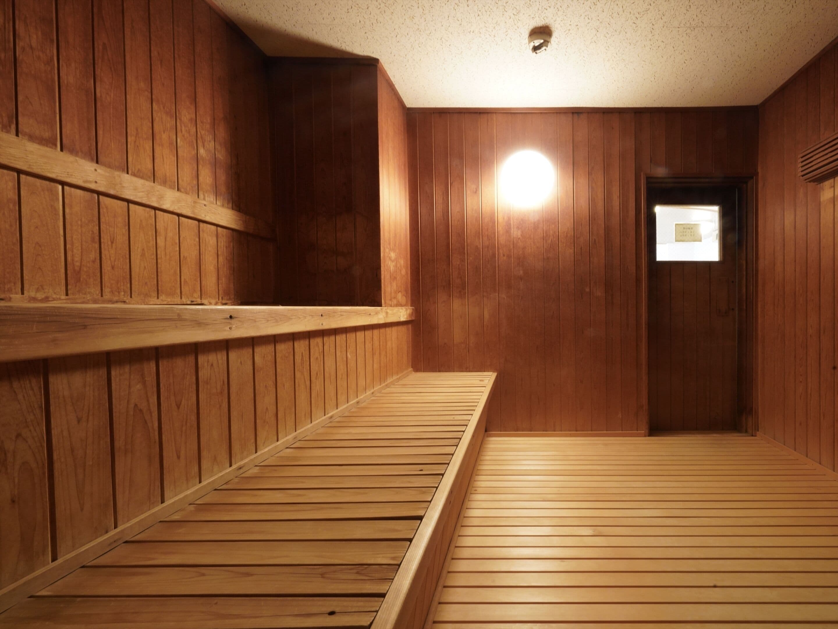 A wooden sauna room with benches and a door.