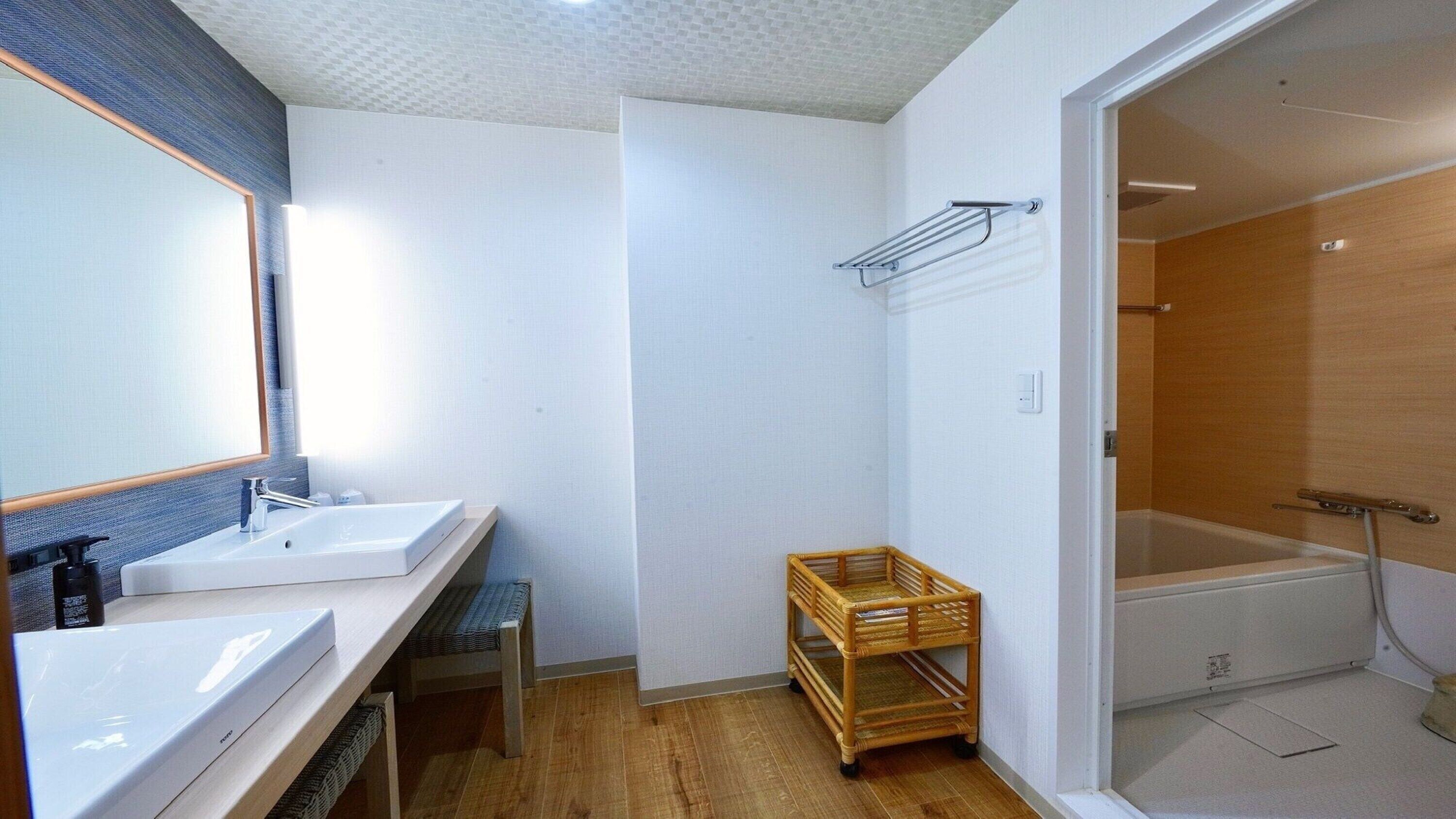 Une salle de bain avec deux lavabos, un miroir, une douche et un petit chariot en bois.