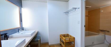 A bathroom with two sinks, a mirror, a shower, and a small wooden cart.