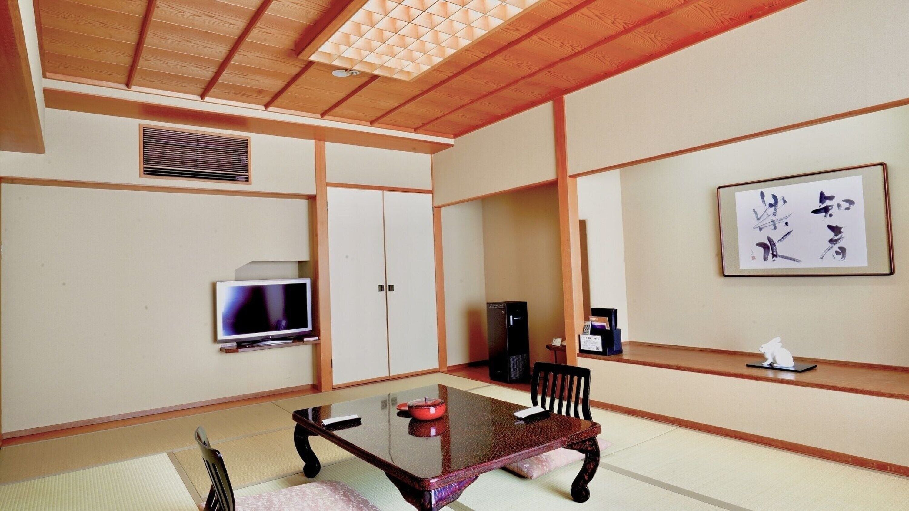A traditional Japanese-style room with tatami flooring, a low table, a television, and a cabinet.